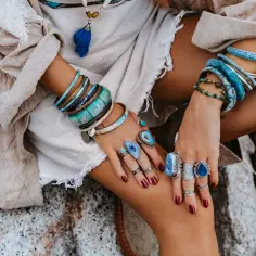 Kobieta w boho stylu nosi liczne bransolety i pierścionki z kamieniami, w tym amazonit, znany ze swoich uspokajających właściwości.
