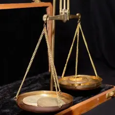 Waga szalkowa z monetami i odważnikami. Zastanawiasz się, ile to jest uncja złota?