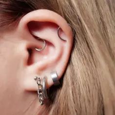Ucho z kilkoma kolczykami, w tym modnym daith piercingiem.