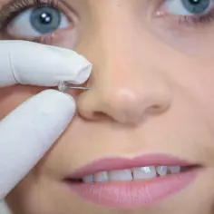 Profesjonalne przekłuwanie nosa, czyli bridge piercing, z błyszczącym kamieniem.